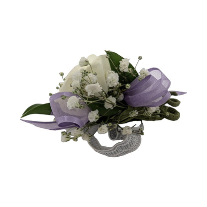 White ranunculus corsage with lavender ribbon on a silver rhinestone bracelet